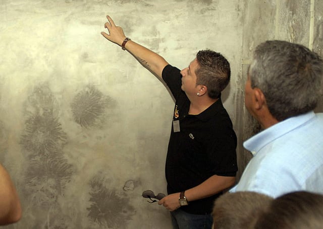 Un parapsicólogo busca caras entre las manchas de humedad de la pared de la casa de las nuevas caras, en Bélmez. Foto: Efe.