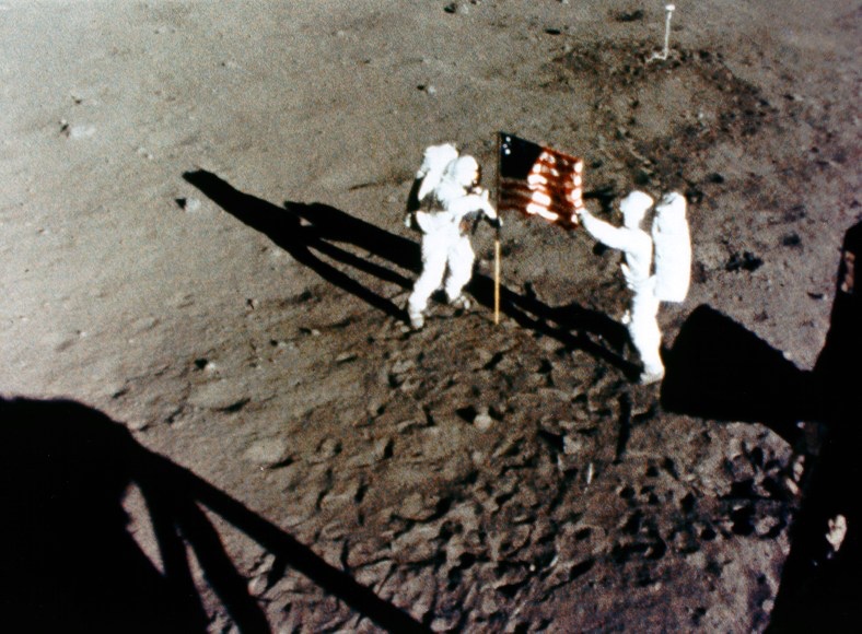 Armstrong y Aldrin, con la bandera. La sombra del primero es mucho más corta que la del segundo. Quienes afirman que la NASA falsificó los alunizajes ven aquí una prueba del engaño. Sin embargo, la sombra de Aldrin es más larga porque está en lo alto de una pequeña elevación y su compañero, más abajo. Foto: NASA.